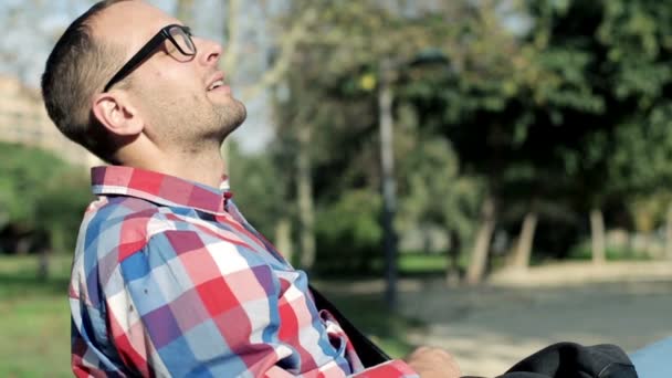 Человек, сидящий на скамейке и глубоко дышащий — стоковое видео