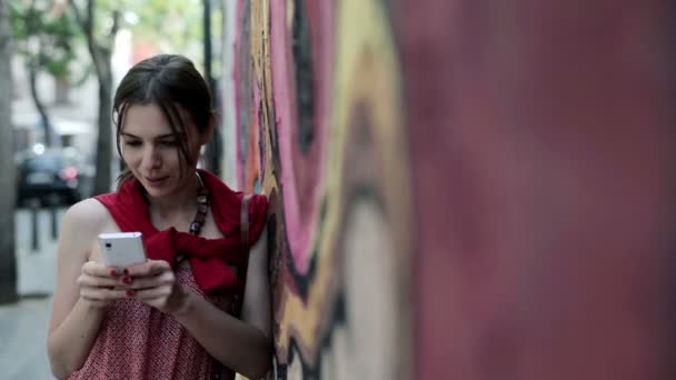 Vrouw texting op smartphone door graffiti muur — Stockvideo