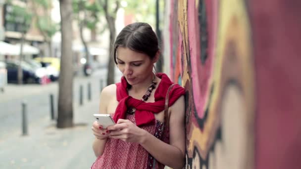 Vrouw texting op smartphone door graffiti muur — Stockvideo