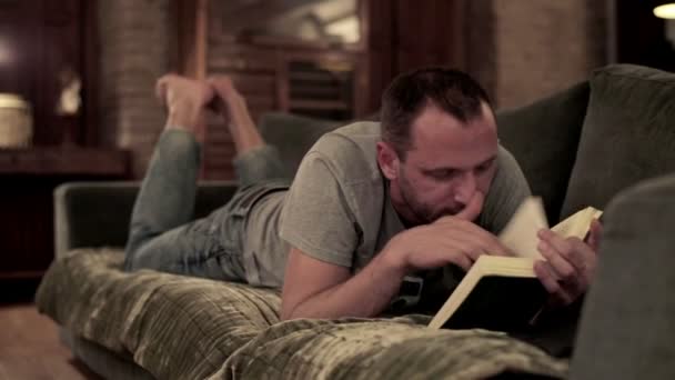 Mann liest Buch zu Hause — Stockvideo