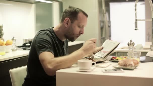 Hombre leyendo el periódico durante la comida — Vídeo de stock