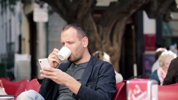 Mann schreibt SMS und trinkt Kaffee — Stockvideo