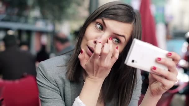 Businesswoman using cellphone as mirror — Stock Video