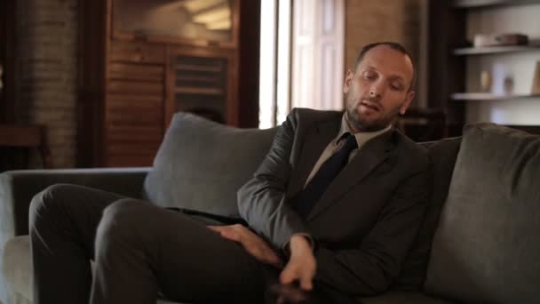 Уставший бизнесмен отдыхает на диване — стоковое видео