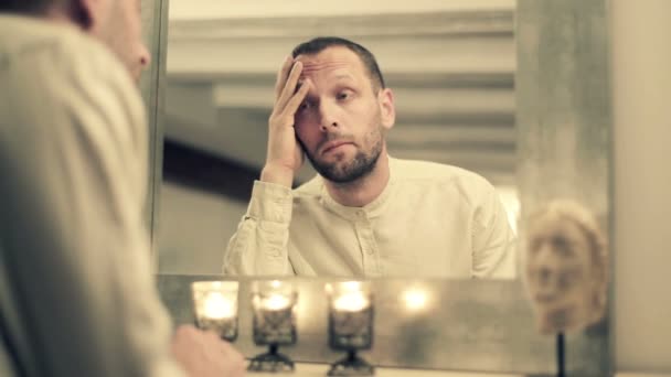 Sad man standing by mirror — Stock Video