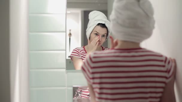 Жінка перевіряє своє обличчя — стокове відео