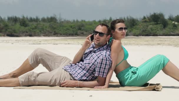 Молода пара говорить на мобільному телефоні на пляжі — стокове відео