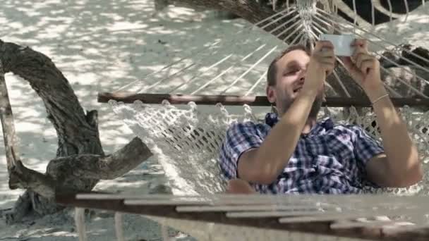 Young man on hammock texting on smartphone — Stock Video