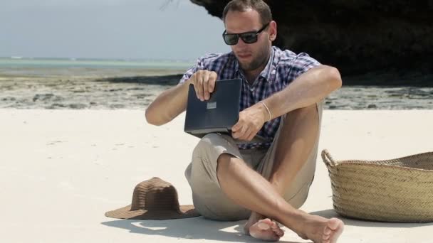 Молодий чоловік з планшетним комп'ютером на красивому екзотичному пляжі — стокове відео
