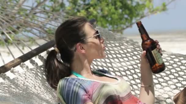 Donna felice su amaca bere birra, spiaggia esotica — Video Stock