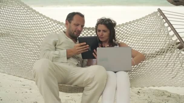 Par med Tablet PC och laptop avkopplande i hängmatta — Stockvideo