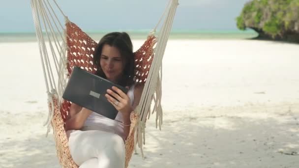 Жінка з планшетом на гамаку — стокове відео