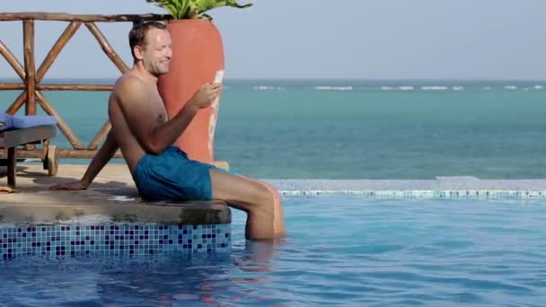 Чоловік зі смартфоном біля басейну — стокове відео