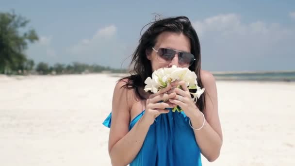 Mulher cheirando flores na praia — Vídeo de Stock