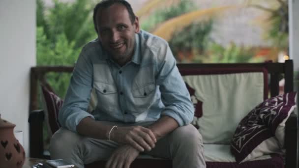 Handsome man sitting on patio — Stock Video