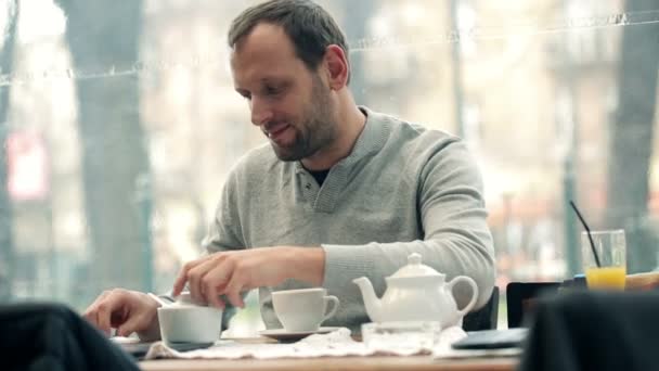 Человек кладет сахар в чашку — стоковое видео