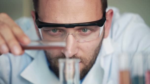 Scientist pouring chemicals into flask — Stock Video