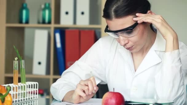 Bioquímica femenina examina manzana — Vídeo de stock