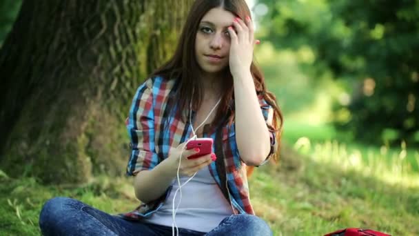 女性は公園で音楽に耳を傾ける — ストック動画