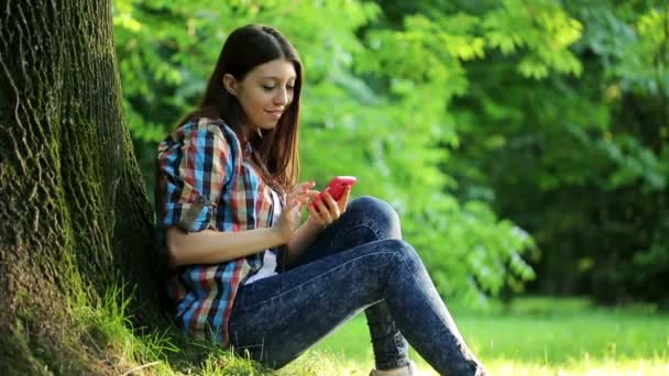 Mujer mensajes de texto sms en el parque — Vídeos de Stock