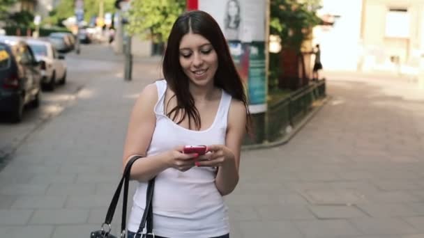 Frau schreibt SMS auf Smartphone, geht in der Stadt spazieren — Stockvideo