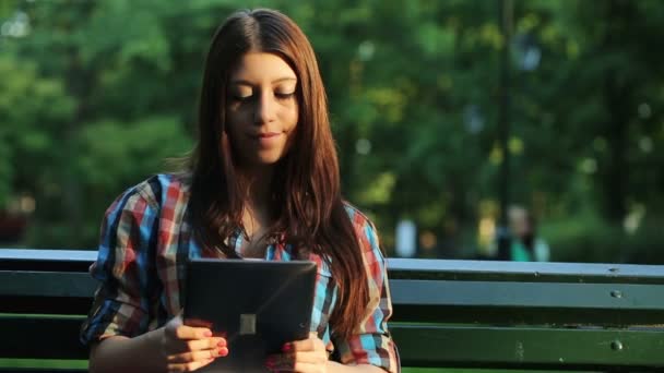 Adolescente con la tableta sentarse en el banco — Vídeos de Stock