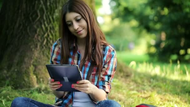 Studentin mit Tablet sitzt im Park — Stockvideo