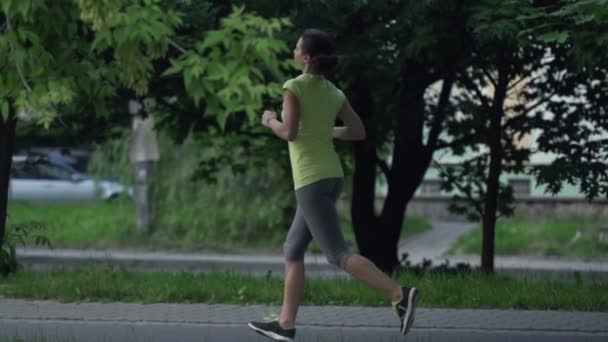 Ung kvinna jogging i stadsparken — Stockvideo