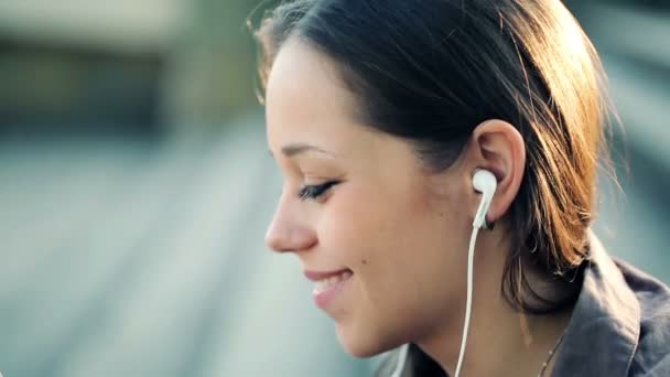 Vrouw luisteren muziek in de stad — Stockvideo