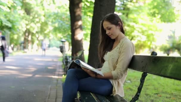 Vrouw in park lezing tijdschrift — Stockvideo