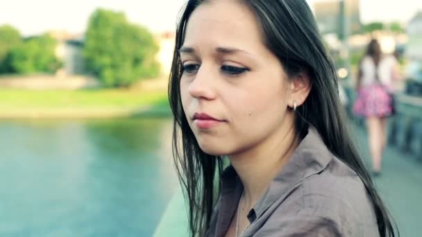 Грустная женщина смотрит на реку в городе — стоковое видео
