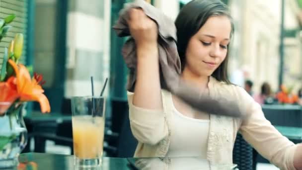 Vrouw haar nieuwe kleren in café controleren — Stockvideo