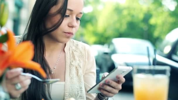 Mujer mensajes de texto y comer postre en la cafetería — Vídeos de Stock