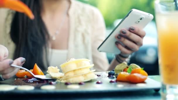Frau schreibt SMS und isst Dessert im Café — Stockvideo