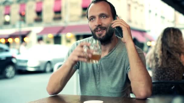 Мужчина разговаривает по телефону и пьет пиво — стоковое видео