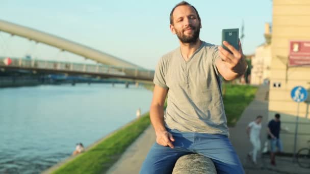 Man tar selfie foto på väggen vid floden — Stockvideo