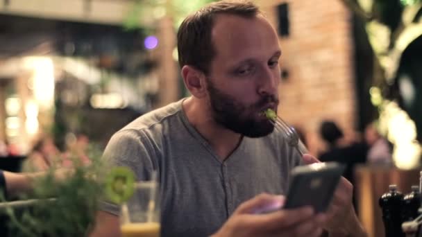 Mann mit Smartphone isst Salat — Stockvideo