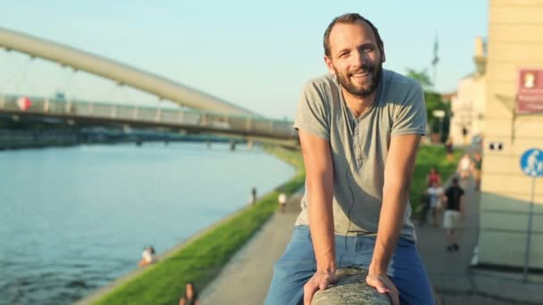 Joven sentado junto al río — Vídeo de stock