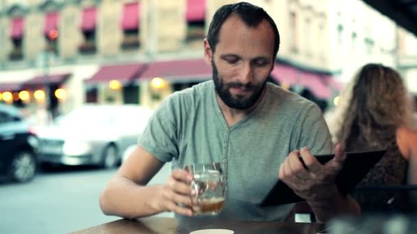 Человек с планшетным компьютером пьет пиво — стоковое видео