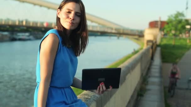 Mujer con tableta sentada junto al río — Vídeos de Stock