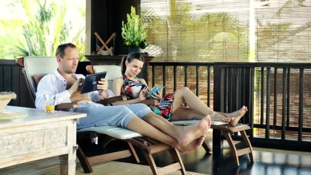 Vrouw met smartphone, man met tablet op terras — Stockvideo