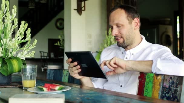 Man with tablet sitting by table — Stock Video