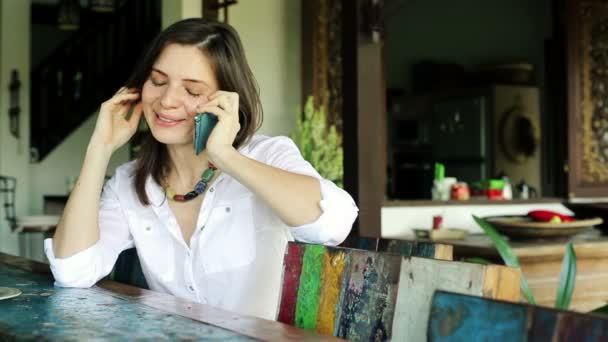 Женщина болтает по телефону за столом — стоковое видео