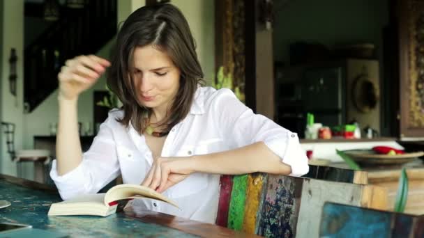 Mujer leyendo libro junto a la mesa — Vídeos de Stock