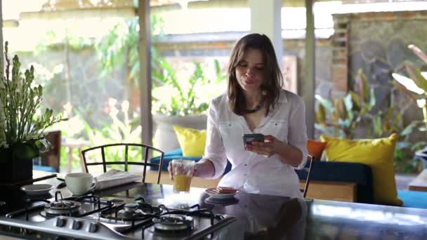 Mujer mensajes de texto en el teléfono inteligente, beber jugo — Vídeos de Stock