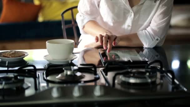 Mulher que navega fotos no tablet na cozinha — Vídeo de Stock