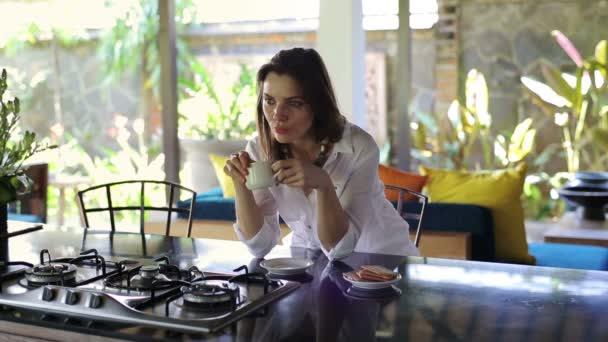 Сумна жінка п'є каву на кухні — стокове відео