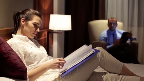 Mujer en la cama leyendo documentos por la noche — Vídeo de stock