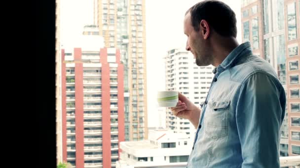 Mann trinkt Kaffee auf Balkon — Stockvideo
