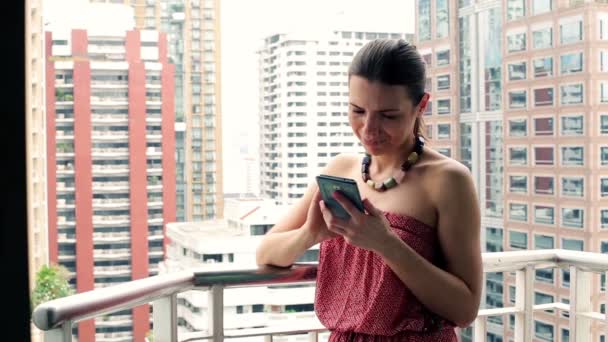 Женщина пишет смс на смартфоне на балконе — стоковое видео